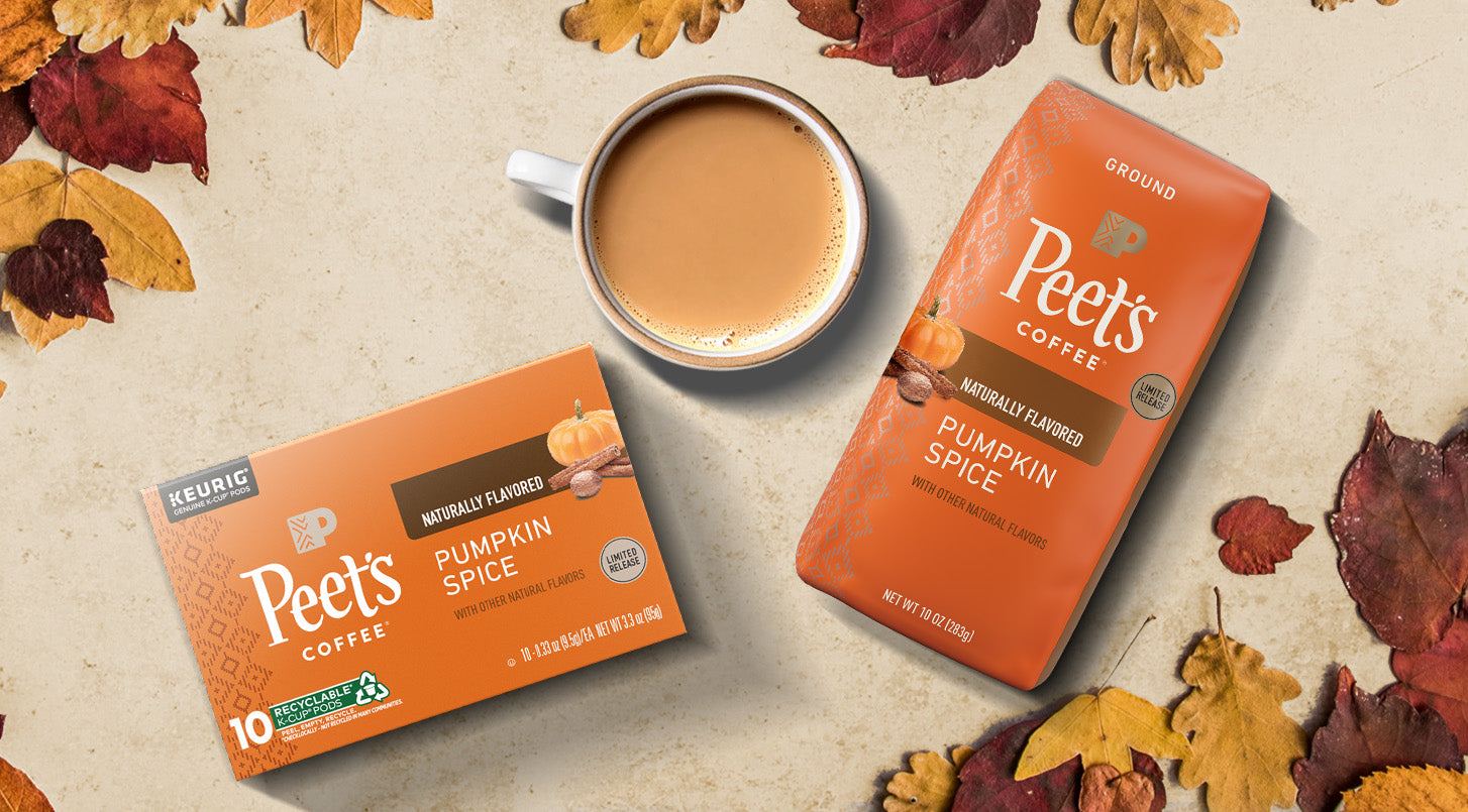 Peet's Coffee Pumpkin Spice coffee grounds and k-cups on a beige counter with autumn leaves