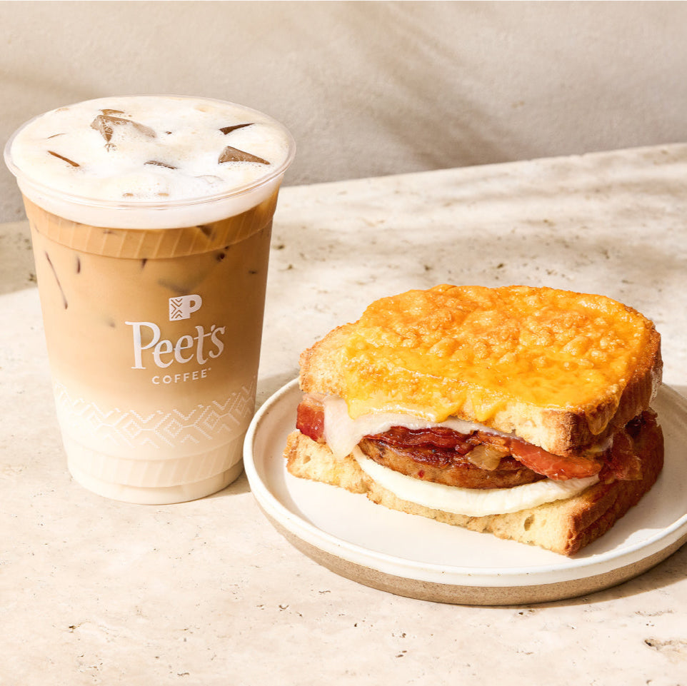 Iced coffee from Peet's Coffee and a sandwich on a plate with a neutral background