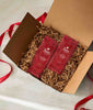 Two red Peet's coffee packages- Holiday Blend and Holiday Blend Decaf in a gift box with brown paper and red ribbon.